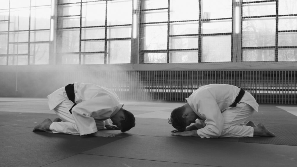 Two martial artists in training hall bowing as a sign of respect, grayscale image.