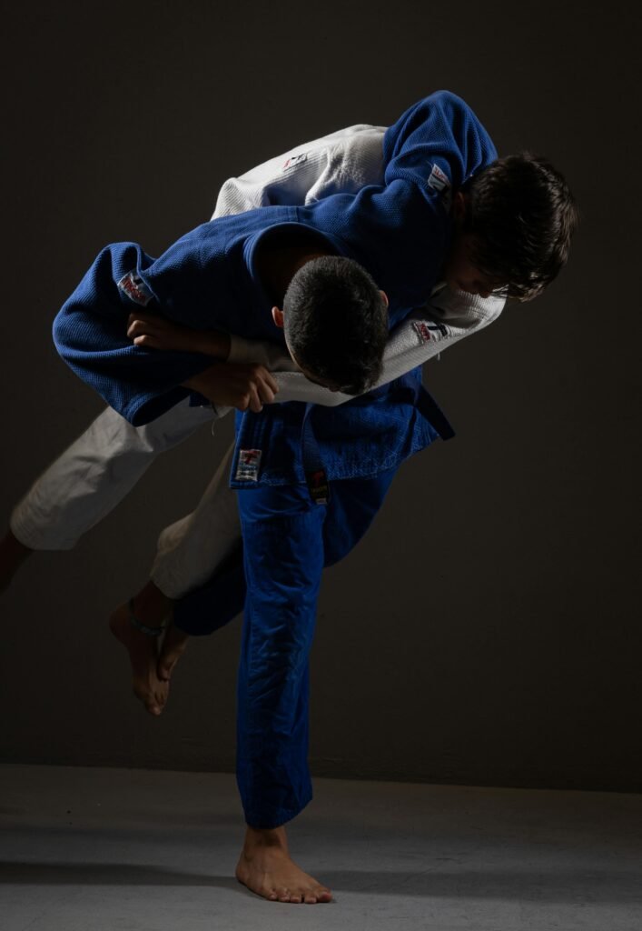 Two judo practitioners engage in a dynamic throw during a competitive match indoors.