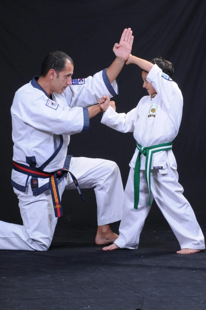 An instructor and child practicing martial arts techniques in traditional uniforms.